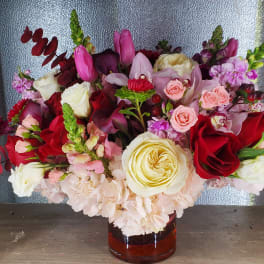 Mixed bouquet of red, pink, and white flowers in a glass vase