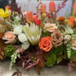 Low floral arrangement with peach, coral, white, and yellow blooms