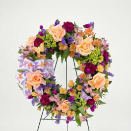 Butterfly-themed floral wreath with peach roses and purple flowers on an easel