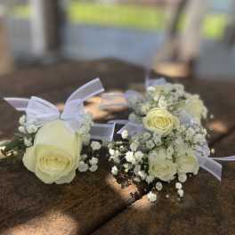 White rose boutonnieres with baby's breath and ribbon ties