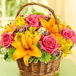 Basket of pink roses and orange lilies with yellow flowers