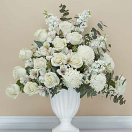 White rose arrangement in a white urn vase