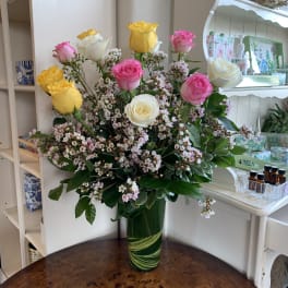 Bouquet of pink, yellow, and white roses in a green glass vase