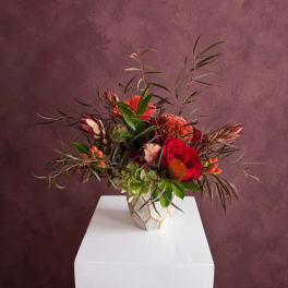 Mixed floral arrangement with red roses in a patterned vase
