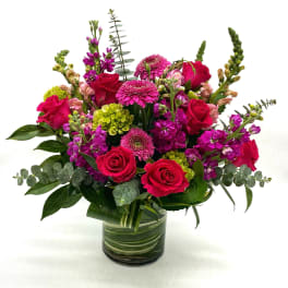 Bouquet of pink roses and magenta flowers in a glass vase