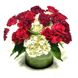 Red roses and white hydrangeas in a green glass vase