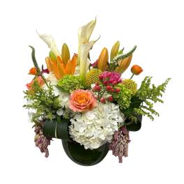 Colorful floral arrangement in a dark glass vase with lilies and roses
