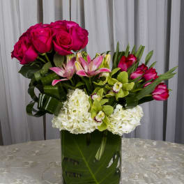 Pink roses, lilies, orchids, and white hydrangeas in a glass vase