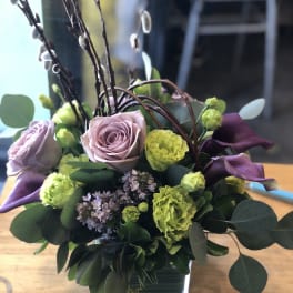 Lavender roses and green carnations in a square glass vase