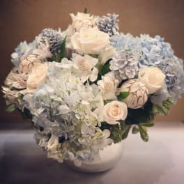 Bouquet of pale roses and blue hydrangeas in a white vase