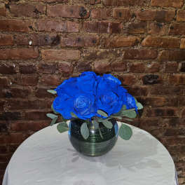 Blue rose bouquet in a dark glass vase on a round table