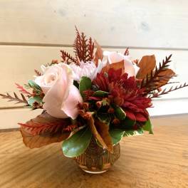Pink roses and red mums arranged in a small glass vase