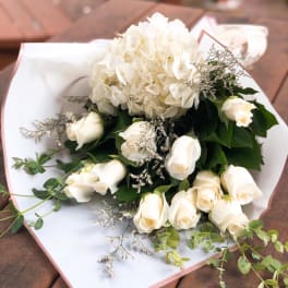 White roses and a white hydrangea bouquet wrapped in white paper