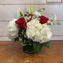Red roses and white hydrangeas arranged in a glass vase