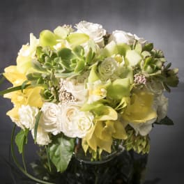 Bouquet of white roses and yellow calla lilies with succulents in a glass vase