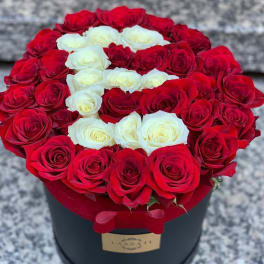 Red and white roses arranged in a round black box