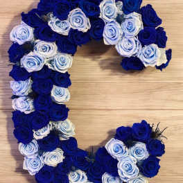 Heart-shaped arrangement of blue and white roses on a wooden surface