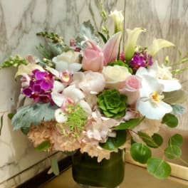 Mixed bouquet of white, pink, and purple flowers in a glass vase
