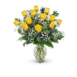 Yellow roses in a clear glass vase with white filler flowers