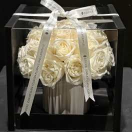 White roses arranged in a black gift box with a ribbon bow
