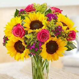 Bouquet of sunflowers and pink roses in a clear glass vase