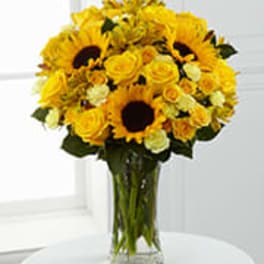 Yellow sunflowers and roses in a clear glass vase
