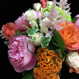 Mixed bouquet with pink peony, cream and orange roses, green hydrangea and orange celosia on black background