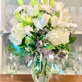 White lilies and roses arranged in a glass vase