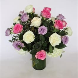 Bouquet of pink, lavender, and white roses in a green glass vase