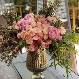 Pink and peach floral arrangement in a metallic vase