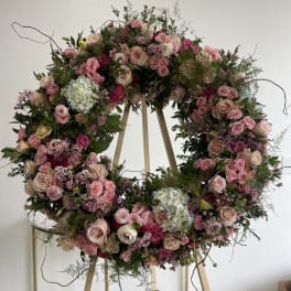 Large pink floral wreath on a wooden stand