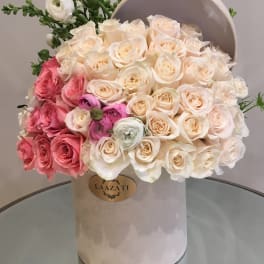 Bouquet of cream and pink roses in a round hatbox