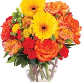 Bouquet of yellow gerbera daisies and orange roses in a clear glass vase