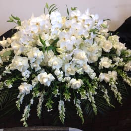 Large white floral arrangement with orchids and roses