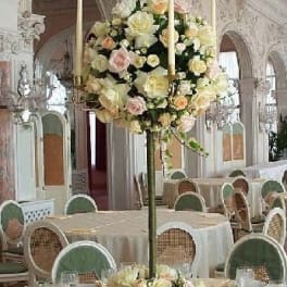 Tall floral centerpiece with pale roses and candles on a banquet table