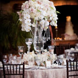 Tall white floral centerpiece on a decorated banquet table