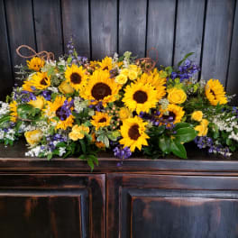 Large floral arrangement with sunflowers, yellow roses, and purple flowers