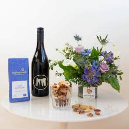 Flower arrangement with wine, chocolates, and nuts on a table