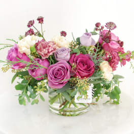 Pink and lavender roses with carnations in a glass vase