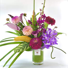 Colorful mixed bouquet in a glass vase with orchids and dahlias