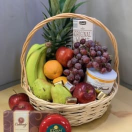 Fruit basket with bananas, grapes, apples, pears, pineapple, cheese, and chocolates