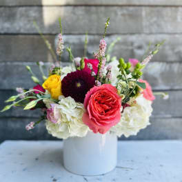 Mixed bouquet of roses, hydrangeas, and other blooms in a white vase