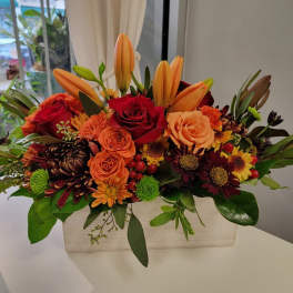 Orange lilies and red roses in a rectangular vase