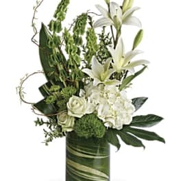 White lilies and roses arranged in a green glass vase