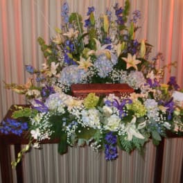 Large floral casket spray with white lilies and blue flowers