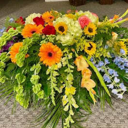 Large colorful floral spray with gerbera daisies, roses, and orchids