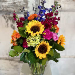 Mixed bouquet with sunflowers, roses, and colorful blooms in a glass vase