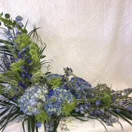 Blue and green floral arrangement with hydrangeas and tall spiky blooms