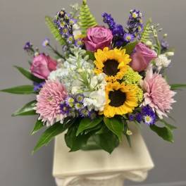 Mixed bouquet with sunflowers, pink roses, and purple flowers in a vase