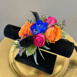 Small bouquet of orange, pink, and blue flowers on a black stand